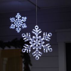 two snowflakes are hanging from the ceiling in front of a house at night