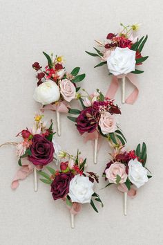 the table is set with flowers and candles on sticks for centerpieces in burgundy, white and pink colors