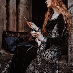 a woman with long red hair wearing a crown and holding a cell phone in her hand