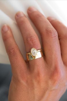 a woman's hand wearing a gold ring with a diamond