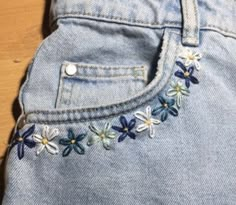 a pair of jeans with embroidered flowers on them