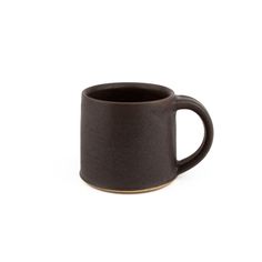 a black coffee mug sitting on top of a white table