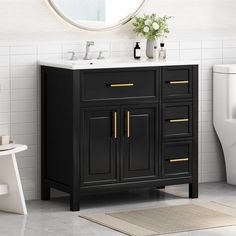 a white toilet sitting next to a black vanity with gold handles on it's doors