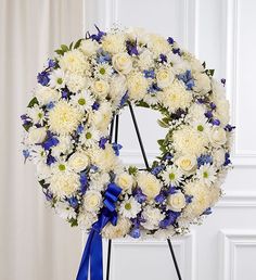 a wreath with white and blue flowers is on display in front of a curtained wall