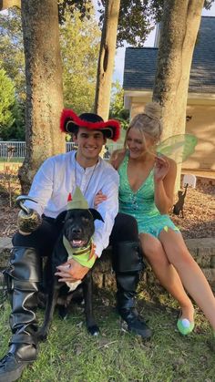 a man and woman dressed up as tinkerbells sitting next to a dog