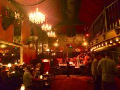 a group of people sitting at tables in a room with chandeliers hanging from the ceiling