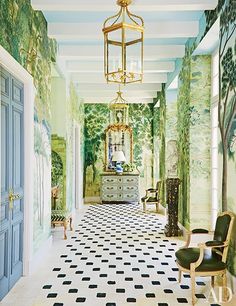 the hallway is decorated with green and white wallpaper, an ornate chandelier, and checkered flooring