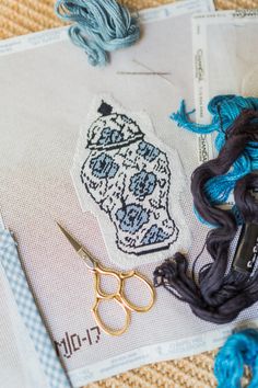 scissors, yarn and thread sitting on top of a piece of paper with an image of a vase