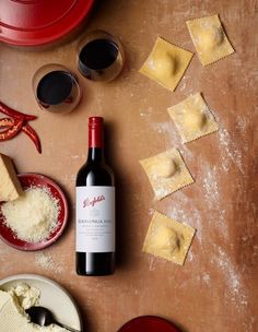 a bottle of wine sitting on top of a table next to some ravioli and sauce