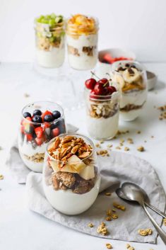 three desserts in small glass jars with spoons on the table next to them