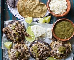 mexican food is laid out on top of a blue tray with limes and other condiments