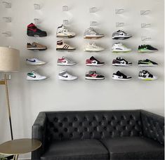 a black couch sitting in front of a white wall with shoes hanging on the wall