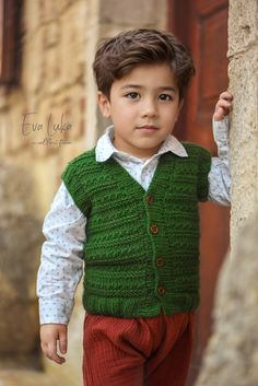 a young boy wearing a green vest and red pants