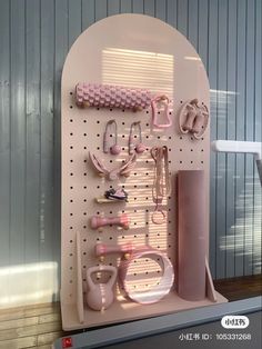 a wall mounted display with pink items on it's sides and hooks attached to the pegboard