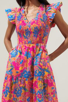 Get a little bit of everything in this fun, vibrant floral dress. Bright multicolored flowers create the Ranchero Floral print that decorates the Sunfire Midi. Lightweight cotton allows you to do your thing all day. It features a flattering smocked bodice with a ruffle V neckline, framed by ruffle cap sleeves. It maintains a fit and flare silhouette with a tiered maxi skirt.- Smocked bodice- Breathable- Pockets- Cap sleeves- Color: Blue OrangeSize + Fit - Model is 5'10" and wearing size XS- Meas Bright Floral Dress, Multicolored Flowers, Do Your Thing, Bright Color Dresses, Wedding 2025, Tiered Maxi Skirt, Tiered Midi Dress, Blue Midi Dress, Summer Wear