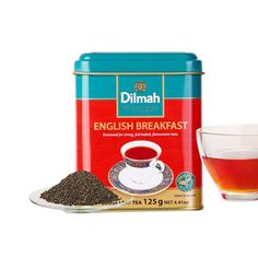 a cup of tea next to a tin of english breakfast tea on a white background