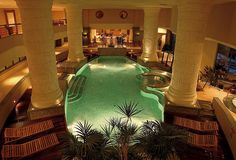 an indoor swimming pool surrounded by columns and palm trees