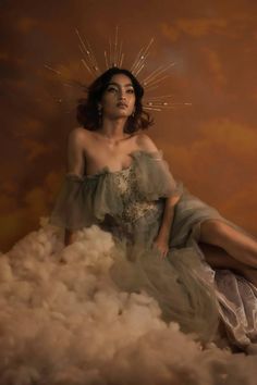 a woman sitting on top of a pile of fluffy white clouds in front of a brown background