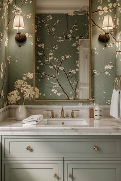 a bathroom with green walls and floral wallpaper on the vanity, along with a gold framed mirror