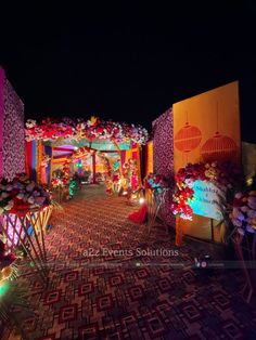 the entrance to an event decorated with colorful lights and flowers on display at night time