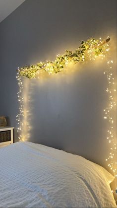 a bed with white sheets and lights on the headboard