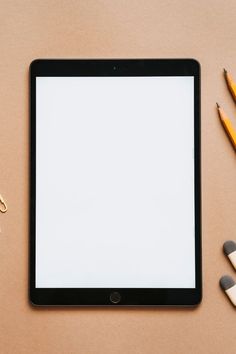 a tablet computer sitting on top of a desk next to pencils and paper clips