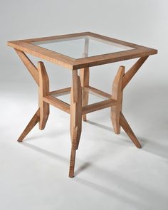 a wooden table with glass top sitting on a white surface in front of a gray background