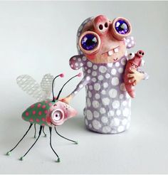 an odd looking figurine is holding a baby bug and another one with big eyes