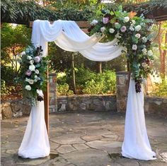 an outdoor wedding arch decorated with flowers and greenery