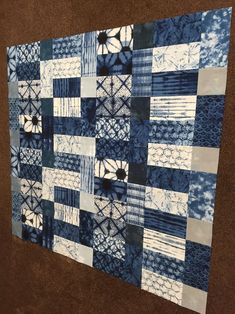 a blue and white quilt hanging on the wall