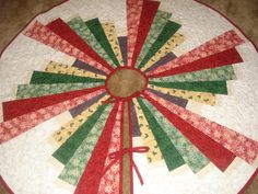 a quilted table topper with red, green and yellow ribbons on it's center