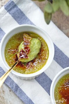 two white bowls filled with green soup on top of a blue and white table cloth