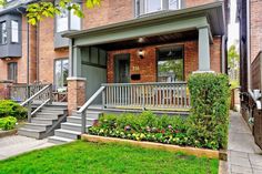 an apartment building with stairs leading up to the front door and flowers on the lawn