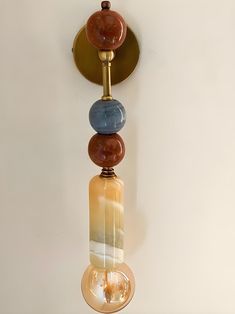 a wall mounted light with three different colored stones on it