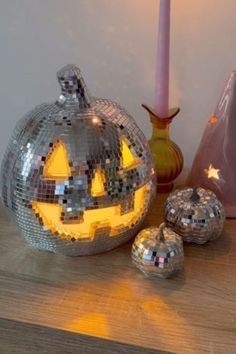 a mirror ball pumpkin sitting on top of a wooden table next to a pink vase