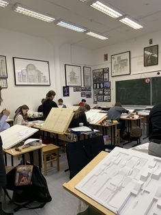 students are sitting at their desks in a classroom with paper work on the walls