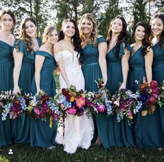 a group of women standing next to each other wearing dresses and holding bouquets in their hands