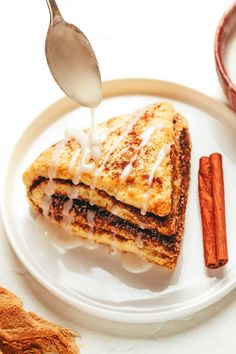 a white plate topped with two slices of french toast and cinnamon sticks next to it