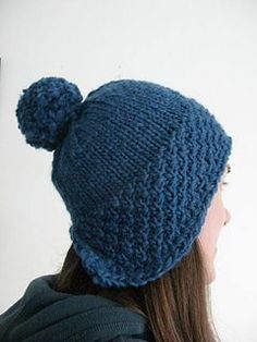 a woman wearing a blue knitted hat with a pom - pom