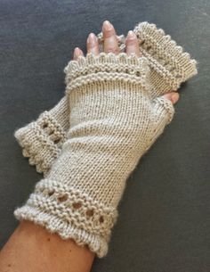 a woman's hand wearing a pair of knitted fingerless gloves