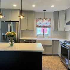 a kitchen with stainless steel appliances and marble counter tops, along with an island in the middle