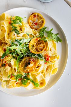 a white plate topped with pasta covered in sauce and garnished with fresh herbs