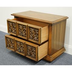 a wooden cabinet with four drawers and carvings on the front, sitting in a room