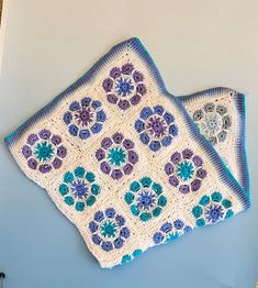 two crocheted dishcloths sitting on top of a blue table next to each other