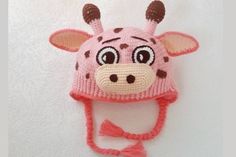 a pink knitted hat with a giraffe face on the front and side