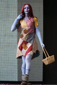 a woman dressed as a zombie walking down the runway with a basket in her hand