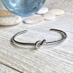 ✦ Stainless Steel✦ Size: 2.25"inner diameter ✦ Inner Circumference is 6.5" but these are super adjustable and can fit larger or smaller wrists by simply squeezing them together or pulling the two sides apart. Super sweet silver love knot bangle bracelet. Love knots represent LOVE, unity, and friendship. Would make perfect bridesmaid bracelets or gifts for someone you love. These will arrive ready for gifting in a cute boho gift box and they usually ship same day or next. KEY FEATURES*-Made of 10 Dainty Handmade Cuff Bracelet For Gift, Dainty Handmade Cuff Bracelet As Gift, Handmade Dainty Cuff Bracelet For Gift, Handmade Dainty Cuff Bracelet As Gift, Sterling Silver Hand Wrapped Cuff Bracelet Gift, Hand Wrapped Sterling Silver Cuff Bracelet Gift, Handmade Silver Bracelet For Best Friend, Silver Cuff Bracelet Bangle For Bridesmaids, Adjustable Silver Bangle For Bridesmaid Gift