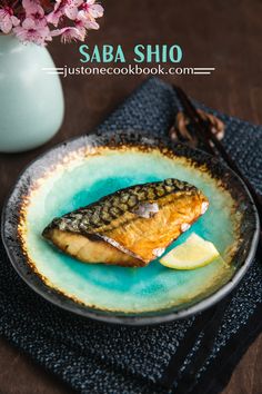 a fish is on a plate with lemon wedges next to a glass of milk