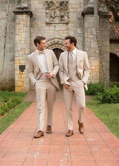 two men in suits walking down a brick walkway