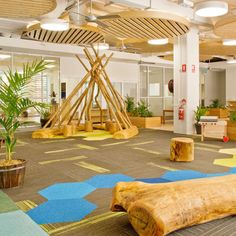 an office with wood logs and plants in the center, on top of carpeted flooring